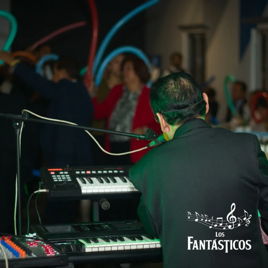 Invitados bailando en la pista de una boda con el tecladista de Los Fantásticos tocando de fondo.